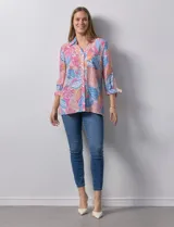 Camisa estampada con hojas en tonos celeste, naranja y verde. Tiene cuello con solapa, abertura central con botones, bolsillos aplicados en la parte delantera y mangas 3/4 con lazo.