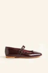 Zapato tipo Mary Jane color borgoña, de charol con correa sobre el empeine y hebilla redonda.