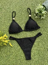 Bikini negra con corpiño triangular que tiene un aplique de piedra en el bretel y bombacha colaless con tiras ajustables laterales.