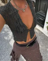 Chaleco de encaje blanco con botones frontales y mangas cortas.