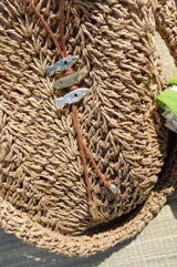 Gargantilla con hilo de algodón color camel y tres dijes de peces realizados en bronce, alpaca y plata 925.