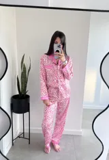 Conjunto de pijama de dos piezas con estampado animal print en tonos rosa y blanco. Incluye una camisa de manga larga con cuello y botones, y un pantalón largo con cintura elástica.