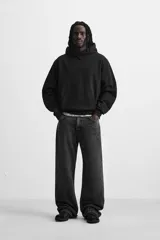 Sudadera con capucha gris confeccionada en tejido de algodón con interior rizo. Tiene manga larga, bolsillo frontal tipo canguro y acabados en rib.
