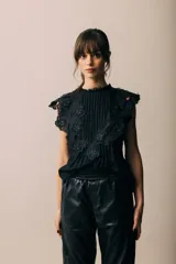 Blusa negra sin mangas con cuello redondo, detalle de volados de encaje con apliques y pinzas verticales en el frente.