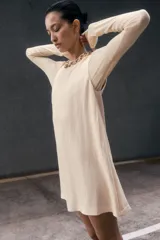 Vestido corto sin mangas color beige. Modelo levemente evasé con escote redondo, abertura de cerradura con botón oculto en la nuca y bajo recto. Parcialmente forrado.