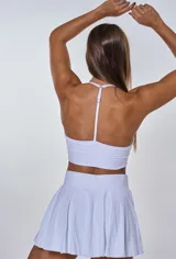 Conjunto deportivo blanco compuesto por top con breteles finos y falda corta tableada.