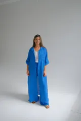 Camisola larga azul francia de lino italiano, con cuello camisero, mangas largas con puños abotonados, cierre frontal con botones y bolsillos de parche en el pecho.