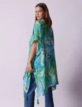 Kimono tejido con estampado abstracto en tonos verde, azul y blanco. Tiene mangas cortas amplias y terminación con borlas verdes en el ruedo.