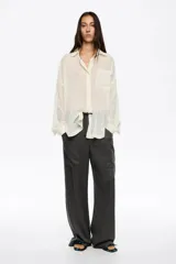 Pantalón de corte recto y tiro bajo, confeccionado en pana de algodón y viscosa color gris oscuro. Presenta bolsillos laterales de gran tamaño tipo cargo y cintura ajustable con cordón.