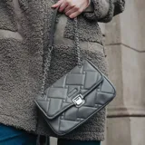 Bandolera rectangular acolchada color gris con solapa y cierre metálico plateado. Incluye correa de cuero y cadena plateada.