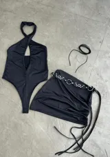 Body negro con escote pronunciado y tirantes cruzados, con falda incorporada.
