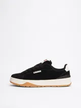 Zapatillas Tommy Jeans de corte bajo, color negro, con exterior de ante, interior de poliéster y suela de goma color caramelo. Presentan un panel a contraste en el talón, logo de Tommy Jeans en la lengüeta y etiqueta de la marca en el lateral.