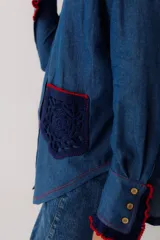 Camisa de jean azul con cuello mao, mangas largas y bolsillo de crochet en el pecho.