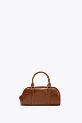 Bolso negro formato mini bowling, con doble compartimento con cierre mediante cremallera, asa de mano y asa bandolera extraíble.