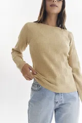 Sweater color beige con diseño geométrico en relieve, de corte entallado y mangas largas.