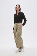 Pantalón cargo de algodón color verde oliva, tiro bajo, con cintura ajustable mediante cordón y piernas anchas y rectas. Presenta bolsillos cargo en los laterales.