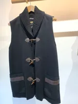 Chaleco negro de lana merino con cuello alto y cierre frontal con broches tipo toggle.