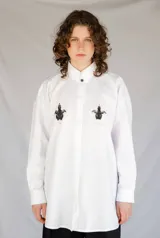 Camisa blanca de algodón con cuello con lengüeta y botón labrado, manga larga con puños y botones, corte oversize y estampado de aves en el delantero.