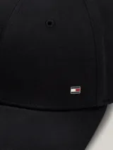 Gorra de béisbol clásica de seis paneles, color negro, confeccionada en algodón. Presenta un pequeño logo esmaltado de Tommy Hilfiger en la parte delantera y un detalle de ribete con los colores distintivos de la marca en el borde de la visera.