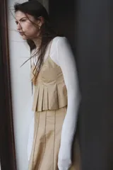 Top corto color beige de algodón con escote en V y breteles spaghetti. Modelo ceñido con cierre lateral oculto y pliegues de caja alrededor de la cintura formando un peplum. Forrado.