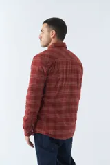 Sobrecamisa de algodón para hombre con interior de corderito, estampado a cuadros en tonos negro, blanco y azul. Tiene cierre de botones, bolsillos tipo cartera y logo en goma. El modelo usa talle M.