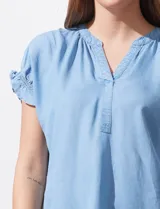 Blusa celeste de lyocell, con cuello a la base y escote en V. Manga corta con detalle de punto smock. Marca Zac & Rachel.