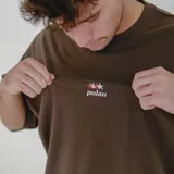 Remera color beige de corte holgado con logo de la marca bordado en el pecho.
