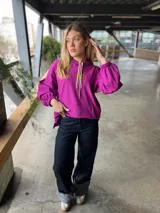 Pantalón de jean azul oscuro de corte recto y tiro alto, con ruedo desflecado y detalle de dobladillo en color gris.