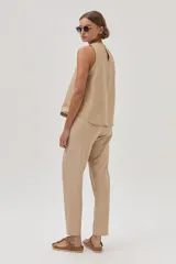 Pantalón chino de lino metalizado color beige, tiro medio-alto y pierna recta. Cuenta con bolsillos laterales y traseros.
