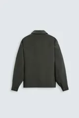 Sobrecamisa negra de corte amplio, con cuello solapa, manga larga con puños abotonados, bolsillos de parche en el pecho, bolsillos laterales y cierre frontal con botones.