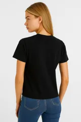 Remera negra de algodón con cuello redondo y estampado de un lazo blanco con estampado floral.