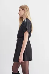 Vestido mini negro con escote cruzado, mangas cortas y cintura elastizada con lazo. Presenta cadenas metálicas en los hombros y en la terminación del lazo.