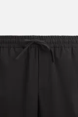 Pantalón color arena de corte recto, confeccionado en tejido elástico. Cuenta con cintura elástica ajustable con cordón, bolsillos laterales y bolsillos de vivo en la parte trasera.