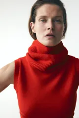 Chaleco de punto color crudo, con cuello alto y sisa amplia.