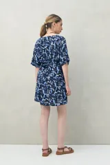 Vestido corto color marrón con estampado de hojas blancas, escote en V, mangas cortas y cintura marcada.