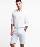Bermuda de hombre en lino color gris claro, de corte recto, con textura discreta, bolsillos laterales y cierre frontal con botón y cremallera.