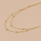 Gargantilla doble de oro amarillo 9k, con cadena fina y pequeñas esferas distribuidas a lo largo de la misma.
