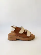 Sandalias de cuero color marrón con plataforma y dos tiras anchas de cuero crudo con velcro.