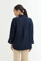 Camisa color beige de corte amplio, con cuello clásico, manga larga y bolsillo en el pecho.