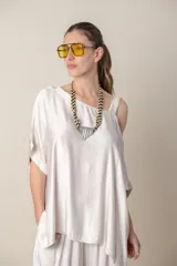 Blusa italiana color blanco, de corte irregular con un hombro descubierto y calce holgado.