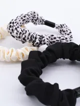 Pack de tres coleros para el pelo, uno color crema, uno con estampado dálmata y uno negro.