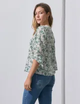 Blusa de gasa color blanco con estampado de hojas verdes, de mangas 3/4 abullonadas con puños elásticos.
