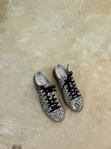 Zapatillas bajas de cuero negro con cordones y suela de goma color caramelo.