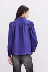 Camisa fluida de color negro, con mangas largas, cuello camisero y puños abotonados.