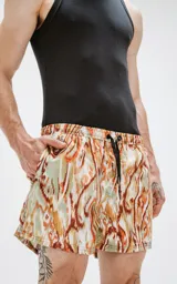 Short de baño con estampado abstracto en tonos verde, naranja y celeste. Tiene cintura elástica con cordón ajustable.