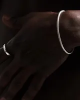 Pulsera rígida plateada con diseño trenzado.
