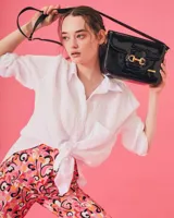 Bandolera color beige con textura símil reptil, cierre con broche metálico dorado y correa larga regulable.