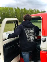 Canguro negro con capucha y cordones ajustables. Estampado en la espalda con la frase "But seek first his kingdom" sobre un diseño floral.