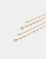 Set de dos pulseras doradas con dijes: una con dijes de trébol y otra con dijes esmaltados de colores.