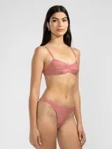 Conjunto de bikini color rosado con textura acanalada. El corpiño es de corte triangular con tirantes finos y la bombacha es tipo colaless.